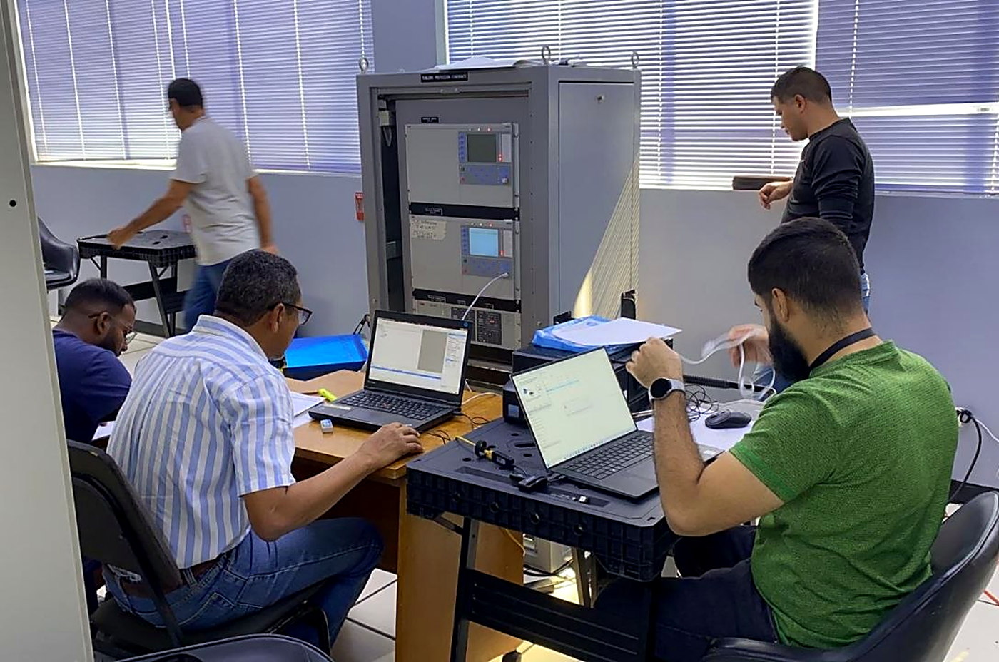 Equipo técnico de ICIS configurando y probando relés de protección sobre un tablero en banco de pruebas